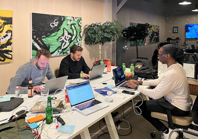 Three developers sitting at a table working on laptops.